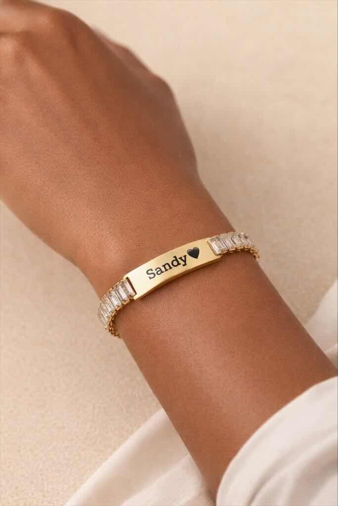 Bracelet élégant en acier inoxydable doré, orné de pierres scintillantes et d’une plaque personnalisable avec le prénom de votre choix. Un bijou raffiné et intemporel qui illumine le poignet et fait un cadeau unique et plein de sens.