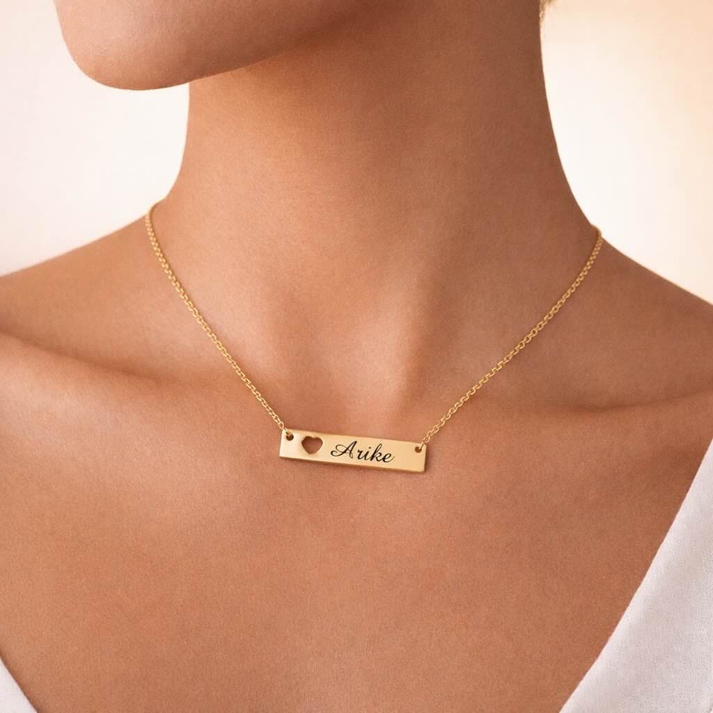 Chaînette élégante en acier inoxydable doré avec plaque personnalisable gravée du prénom de votre choix et un délicat cœur. Un bijou raffiné et sentimental qui apporte une touche unique à votre style.